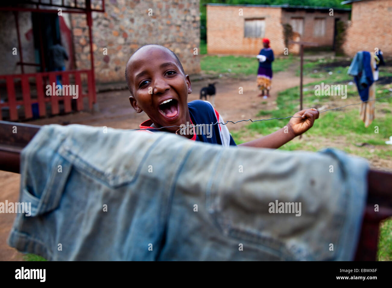 Ragazzo in un cortile guardando sopra uno stendibiancheria ridendo, Burundi Bujumbura Marie, Bujumbura Foto Stock