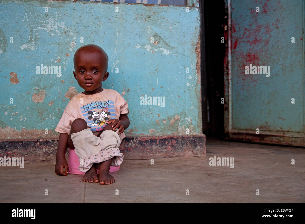 Piccolo Ragazzo seduto su un vasino davanti a una casa, Burundi Bujumbura Marie, Bujumbura Foto Stock