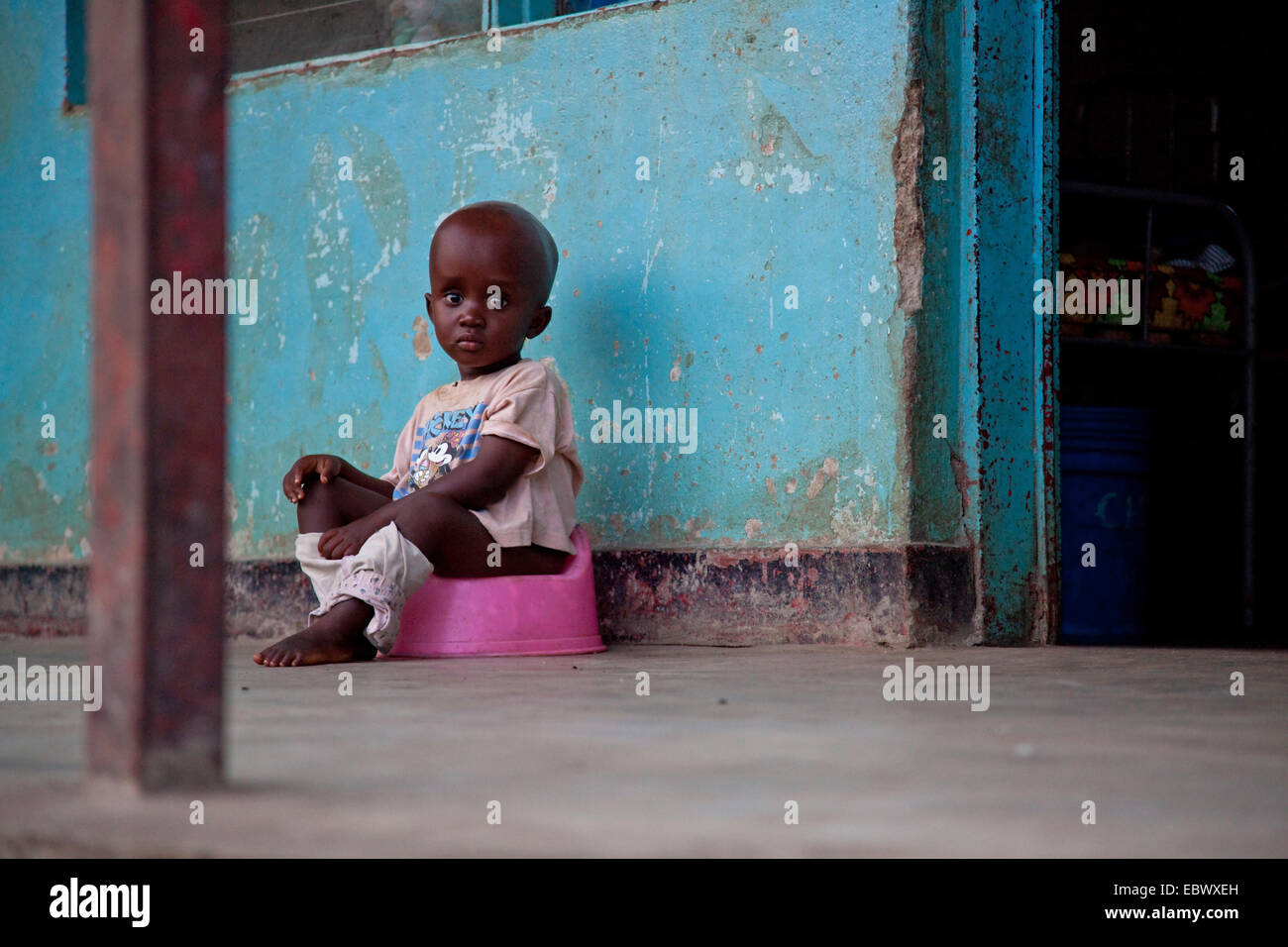Piccolo Ragazzo seduto su un vasino davanti a una casa, Burundi Bujumbura Marie, Bujumbura Foto Stock