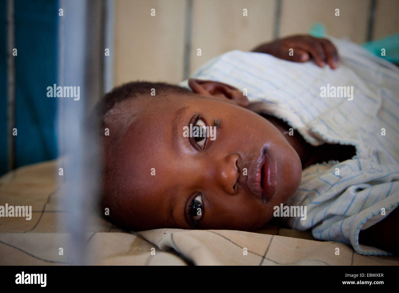 Bambina giacente in letto con un fly strisciando sul suo viso, Burundi Bujumbura Marie, Bujumbura Foto Stock
