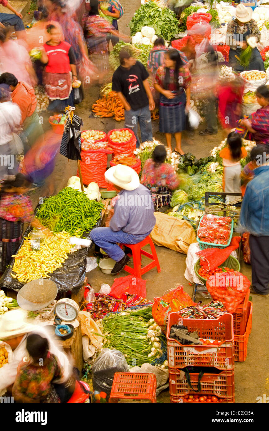 I fornitori locali in insolito angolo birdseye dal di sopra con movimento sfocata in colorati vestiti stampati nella frutta shopping center sul giorno di mercato, Guatemala, Chichicastenango Foto Stock