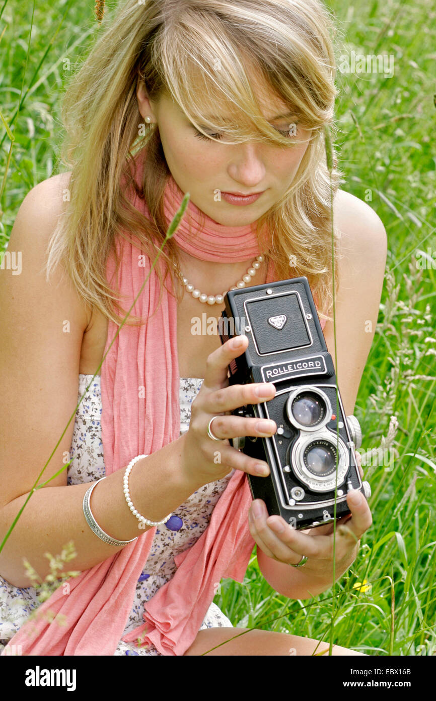 Attraente giovane donna con una vecchia foto seduta della fotocamera in un prato, Germania Foto Stock