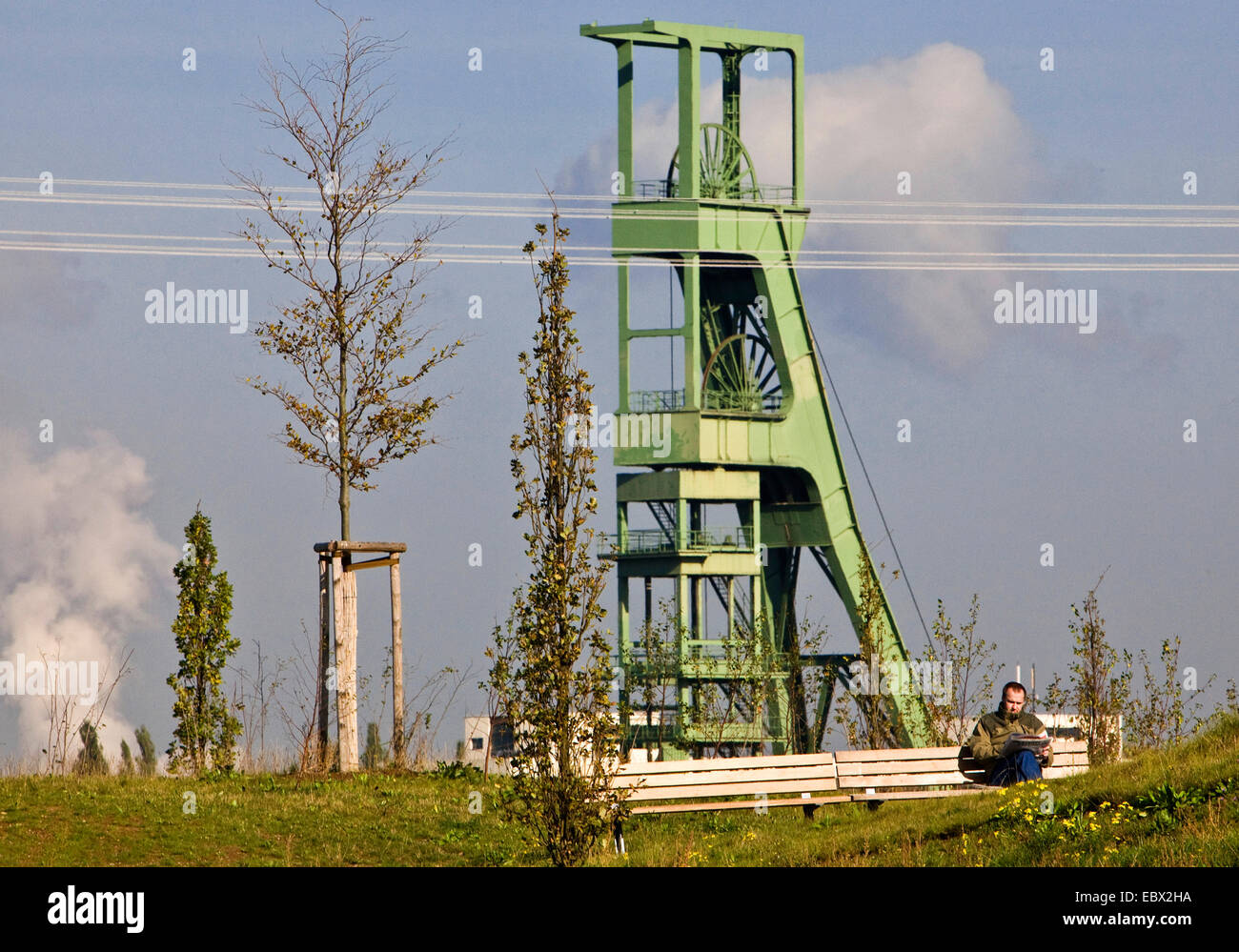 Un uomo seduto su una panchina di fronte un copricapo leggendo un giornale, in Germania, in Renania settentrionale-Vestfalia, la zona della Ruhr, Essen Foto Stock