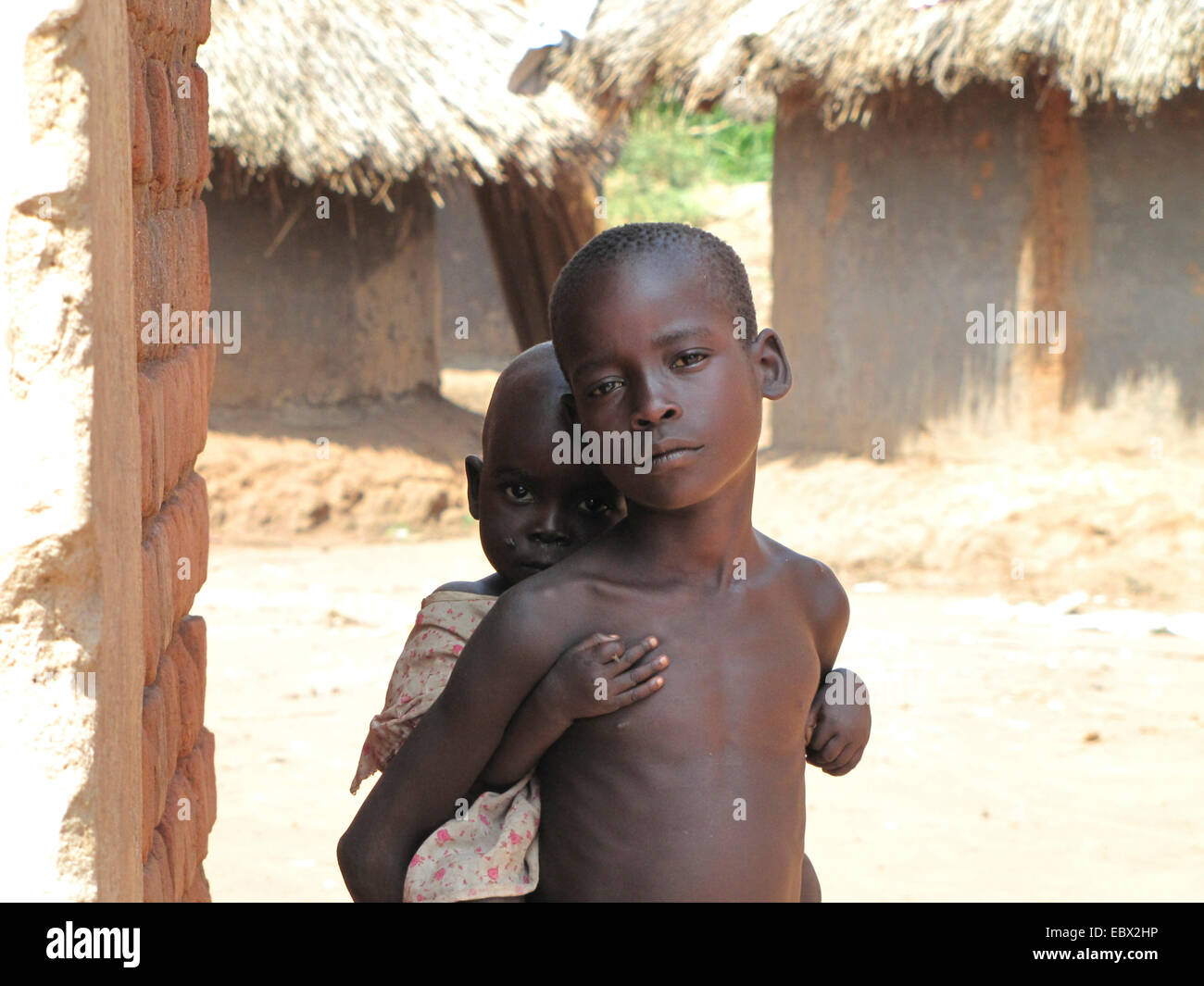 Due bambini piccoli al campo profughi di sfollati nel nord Uganda intorno a Gulu, semplice casa di fango in background, Uganda, John Baptist Odama Arcivescovo di Gulu Foto Stock