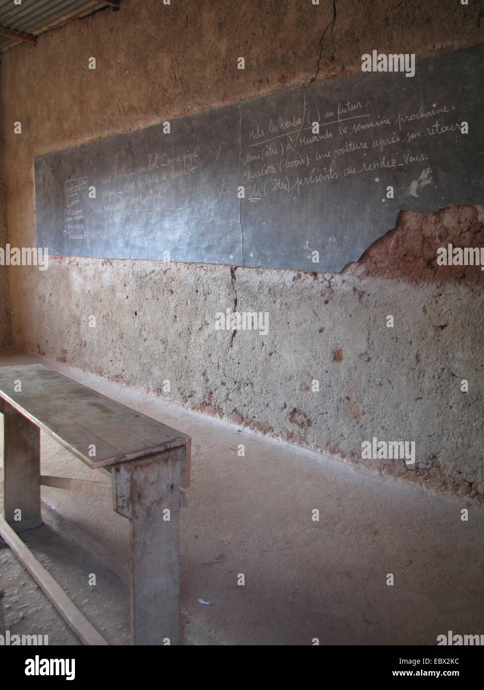 Classe primitiva camera con panca in legno nella parte anteriore del danneggiato lavagna con chalk scrivendo su di esso, il Burundi Bujumbura mairie, Buyenzi Bujumbura Foto Stock