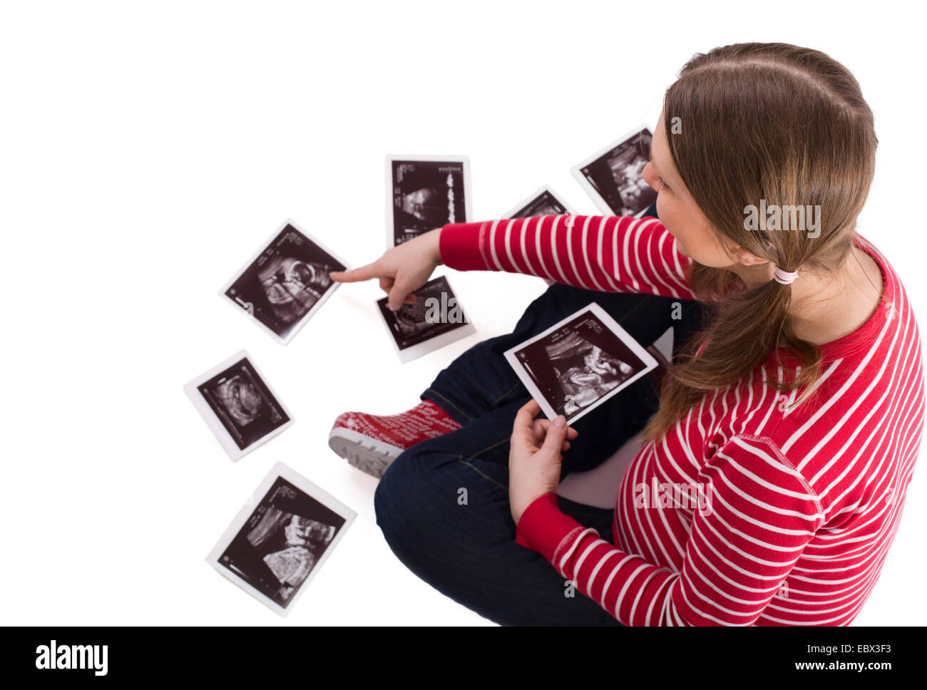 Incinta giovane donna seduta sul pavimento eccitato guardando le immagini ad ultrasuoni del bambino Foto Stock