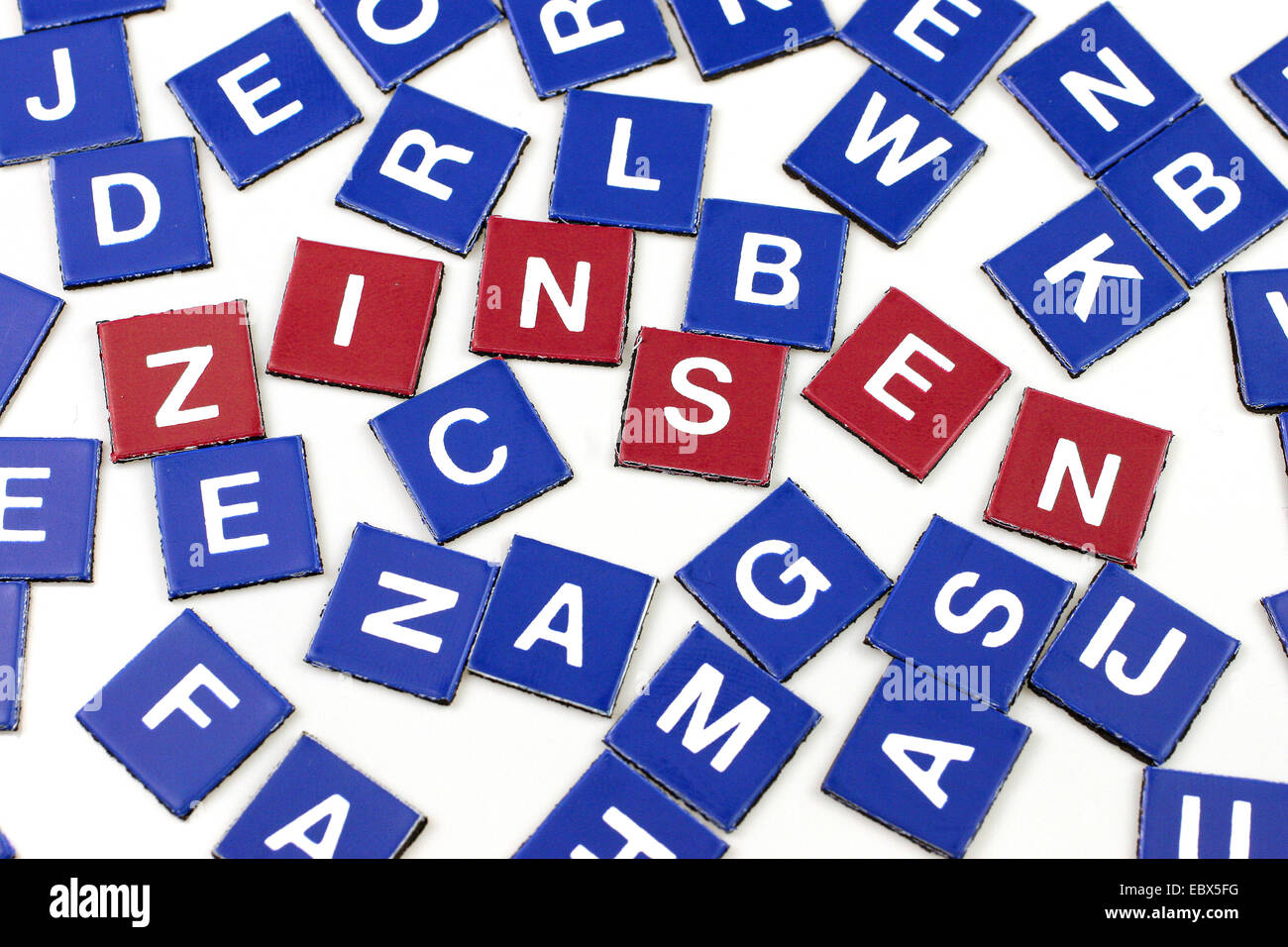 Scrabble blu token, quelli rossi formando la parola Zinsen, interesse (finan). Foto Stock