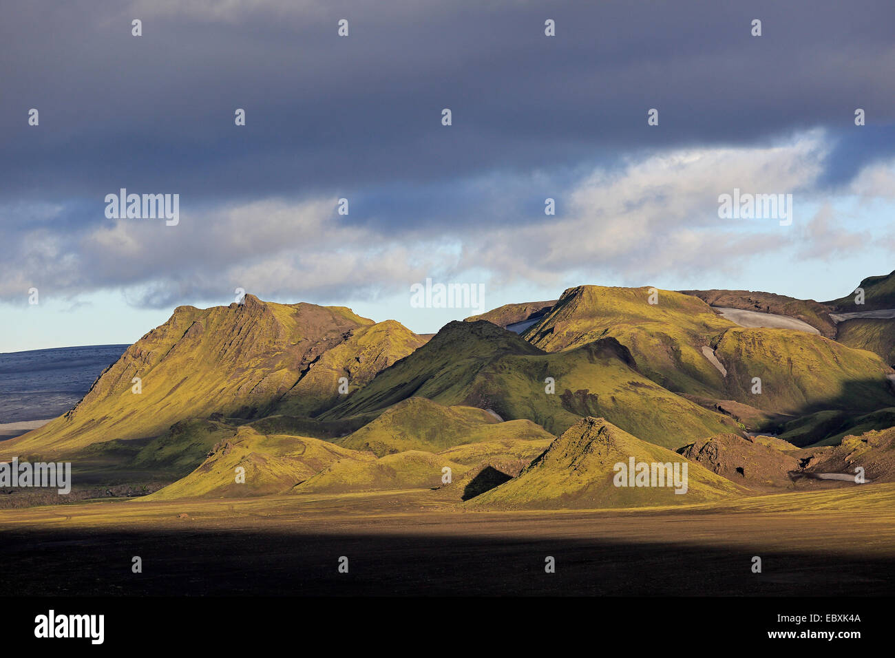 Le montagne che salgono sopra il nero Volcanic Ash Plain sotto il cielo tempestoso Foto Stock