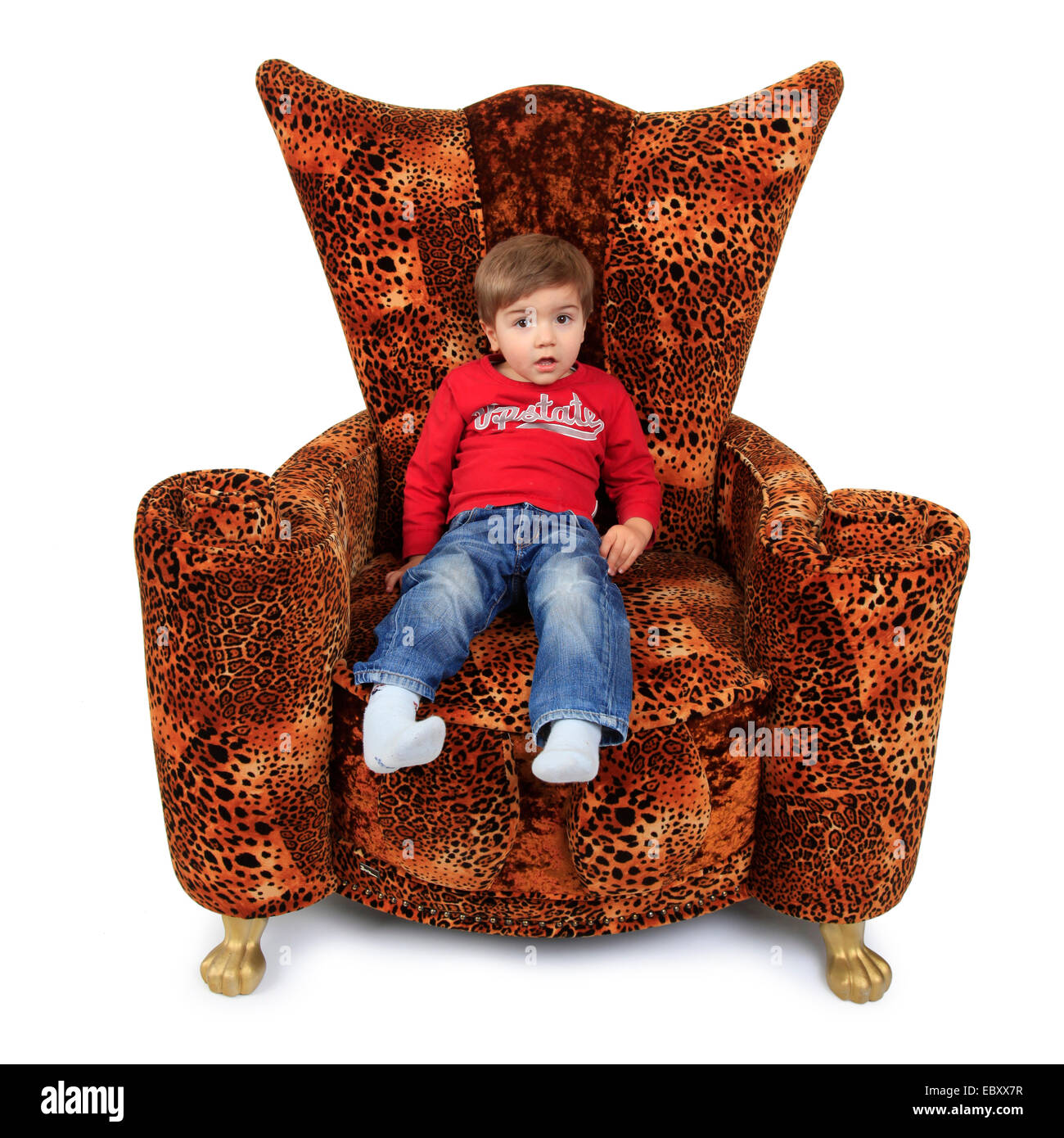 Piccolo Ragazzo seduto su una stravagante troppo grande leopard poltrona con piedini dorati Foto Stock
