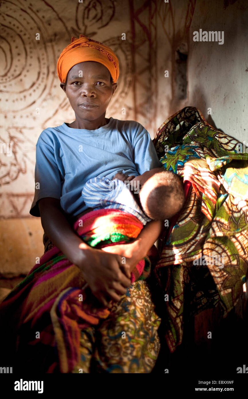 Donna in tradizionali abiti africani allattamento al seno il suo bambino  nel salotto di una semplice casa di fango, Burundi, Karuzi, Buhiga Foto  stock - Alamy