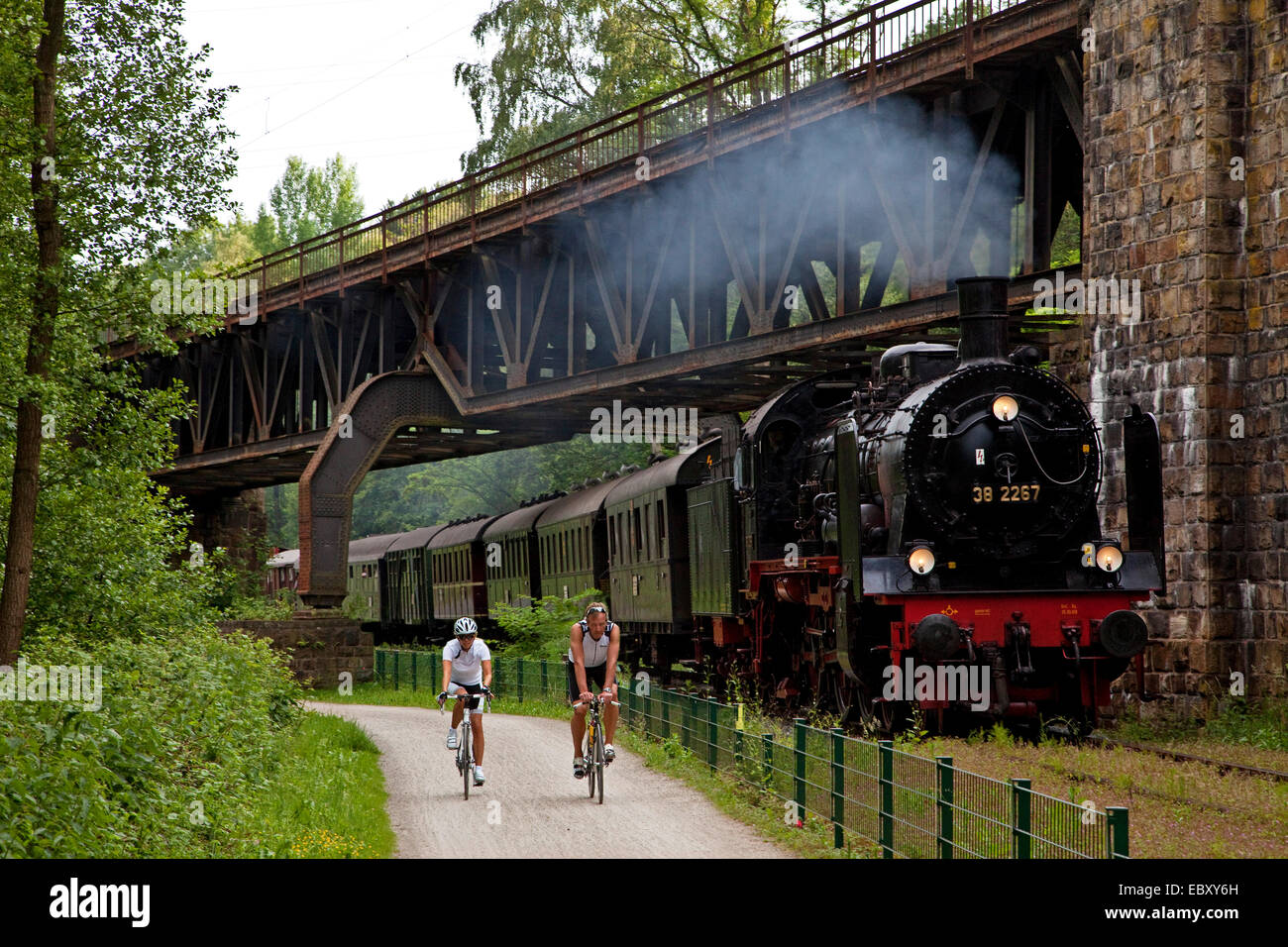 Due ciclisti a valle della Ruhr Cycleway, storico treno a vapore in background, in Germania, in Renania settentrionale-Vestfalia, la zona della Ruhr, Witten Foto Stock