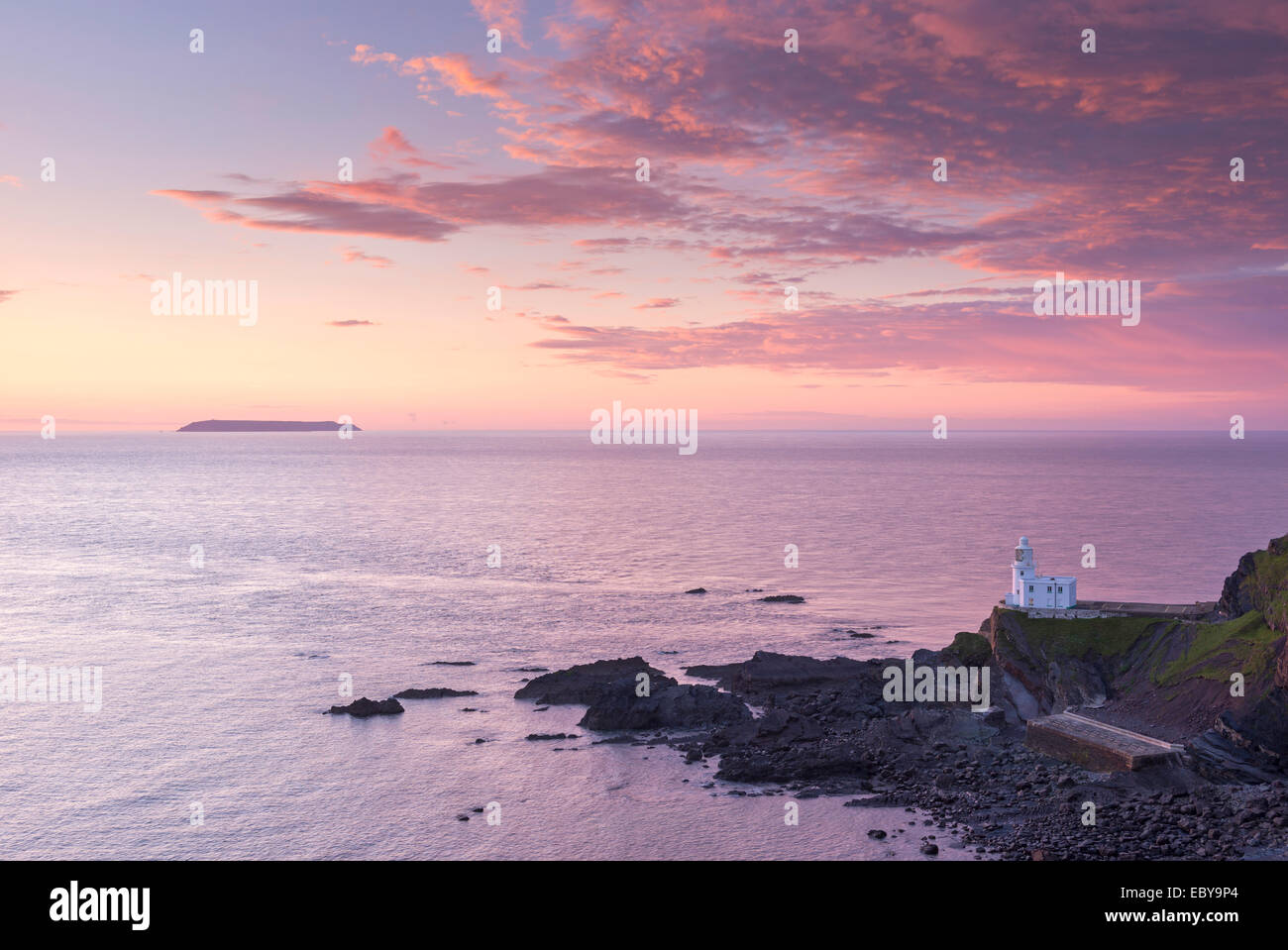 Hartland Point Lighthouse e Lundy Island al di sotto di un tramonto colorato, North Devon, in Inghilterra. Molla (maggio) 2014. Foto Stock