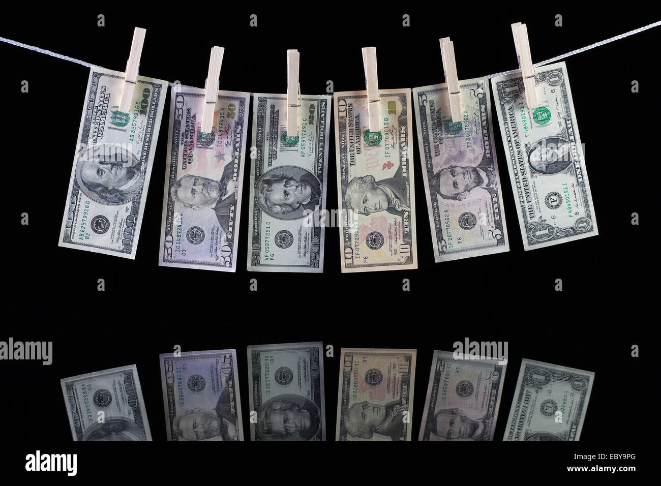 Sporco US dollar banconote pendenti da uno stendibiancheria e riflettendo in vetro Foto Stock