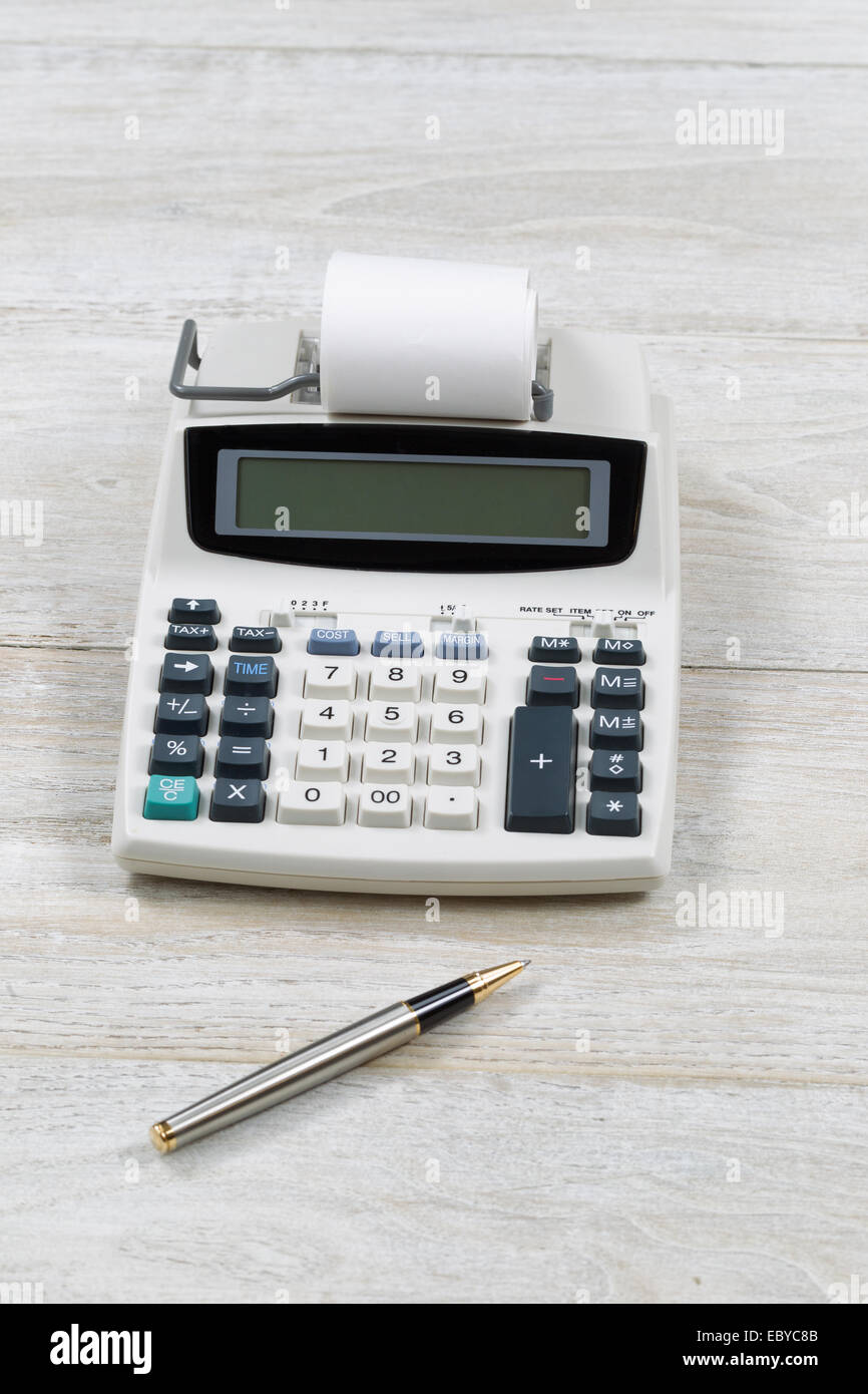 L'immagine verticale di un vecchio calcolatore finanziario con carta e penna sulla scrivania in legno Foto Stock