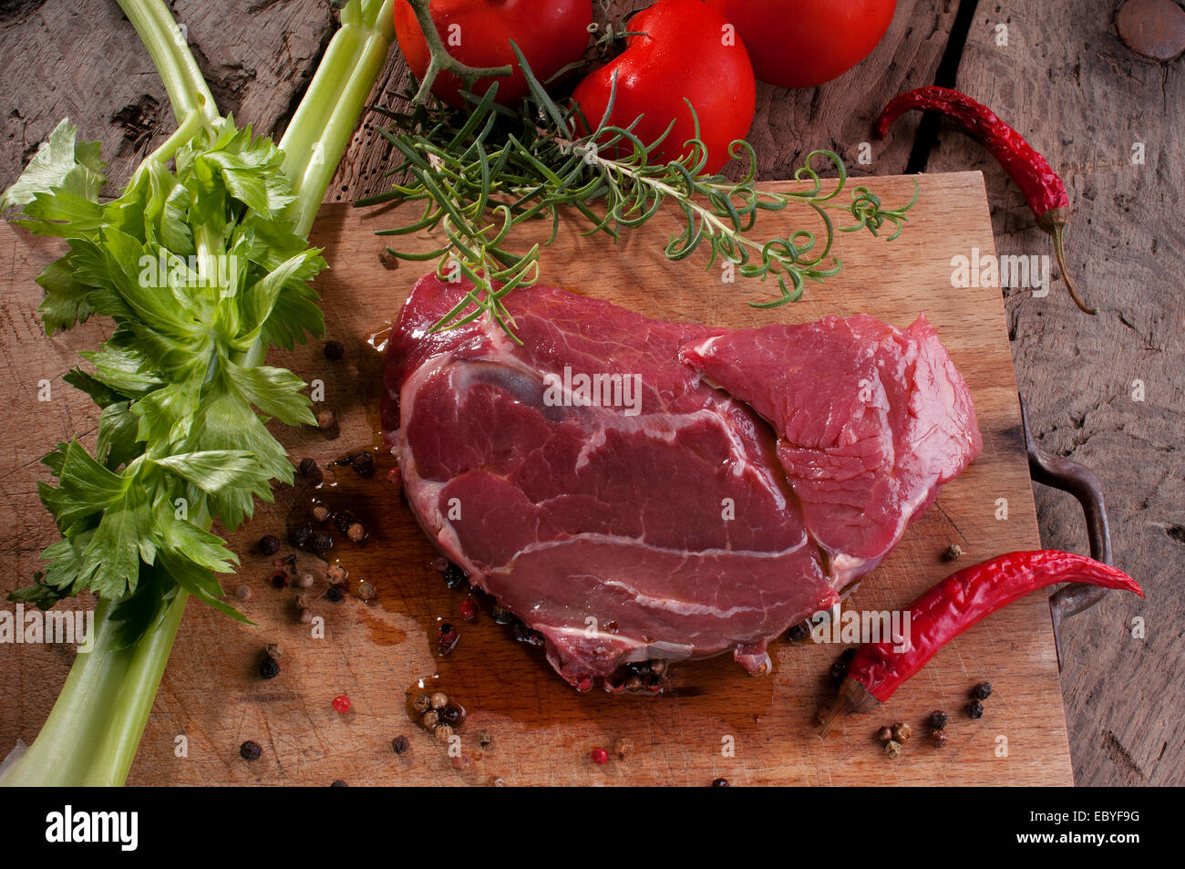 Una bistecca su un tagliere di legno pronto per il barbecue Foto Stock