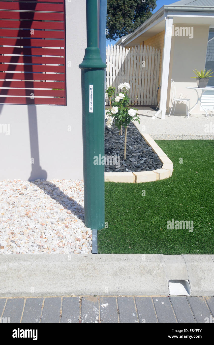Due soluzioni alternative ai prati anteriori quando ci sono acqua giardino restrizioni: ciottoli decorativi e tappeto erboso artificiale Foto Stock