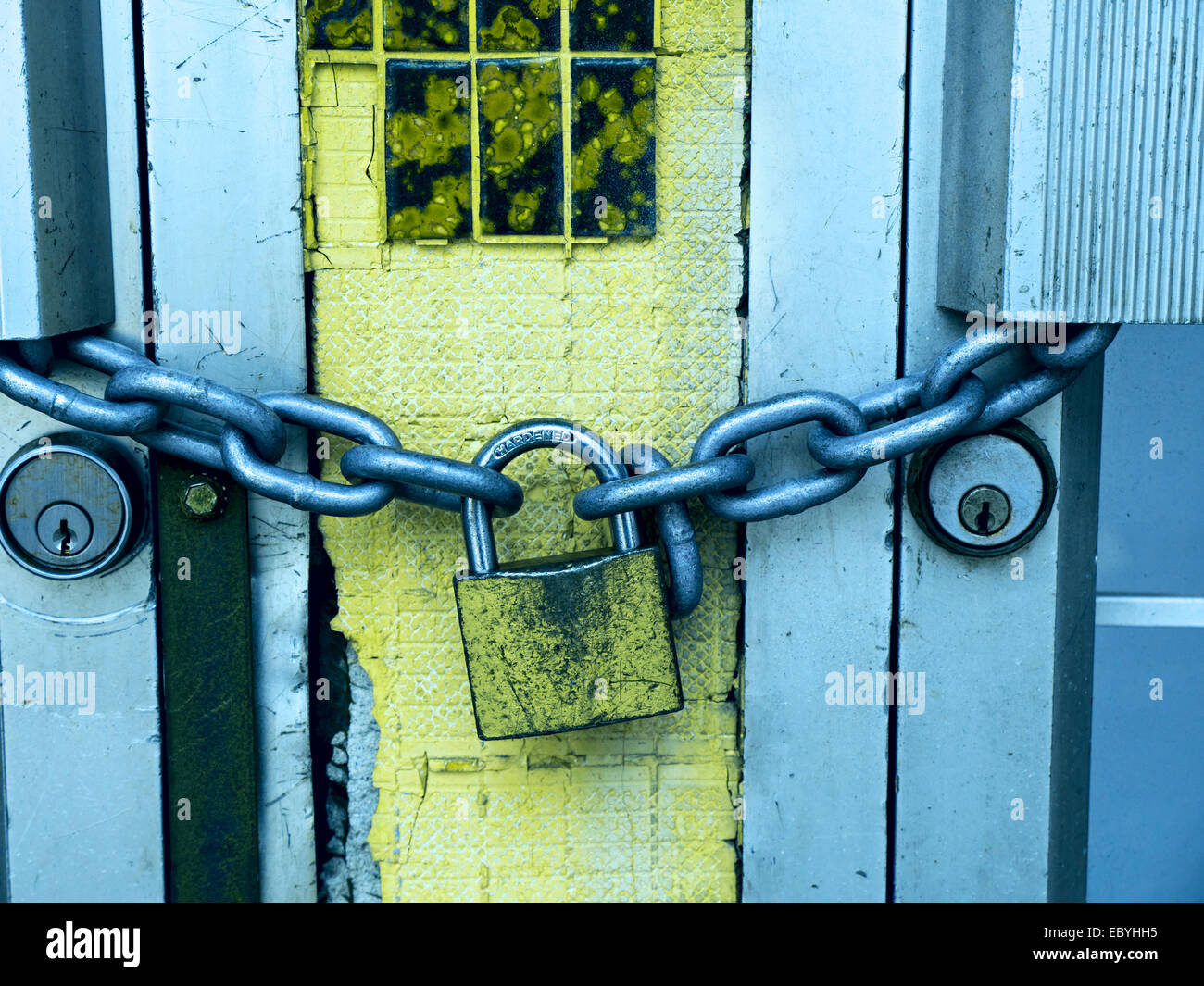 Serratura e catena su un edifici commerciali le porte di metallo; filtrato grunge look Foto Stock