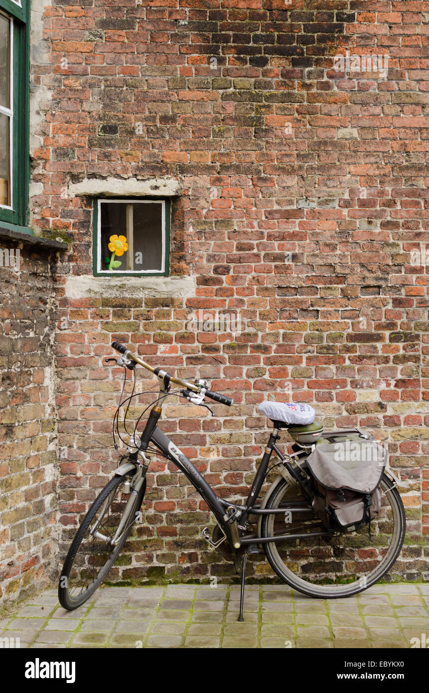 BRUGES, Belgio - OTTOBRE, 25: bici accanto a un muro di mattoni in cui vi è una finestra con fiori artificiali, su ottobre25, 201 Foto Stock