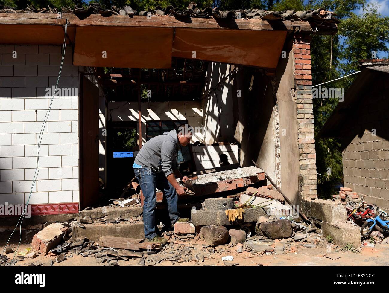 Jinggu cinese della provincia dello Yunnan. 6 dicembre, 2014. Zhou Xinwei della IAM gruppo etnico cerca articoli utili sui resti di una casa crollata a quake-hit Qianying villaggio di Yongping città in Jinggu IAM e Yi contea autonoma, a sud-ovest della Cina di Provincia di Yunnan, 6 dicembre 2014. Sette persone sono rimaste ferite dopo un 5.8-grandezza terremoto Jinggu fin da sabato mattina. Credito: Lin Yiguang/Xinhua/Alamy Live News Foto Stock