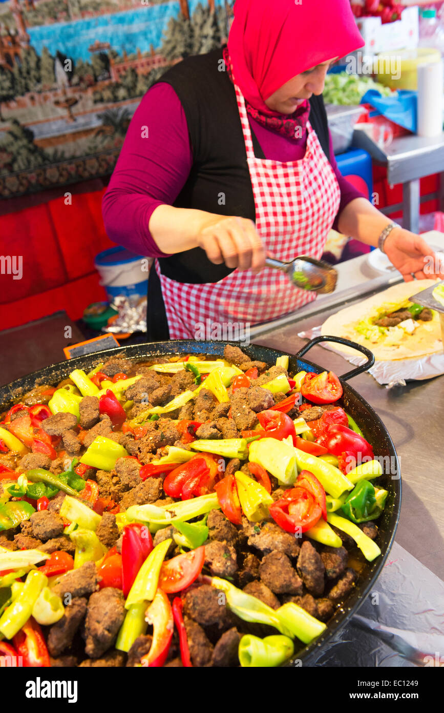 Donna turca che prepara e vende cibo turco a Neukolln del mercato turco. Foto Stock