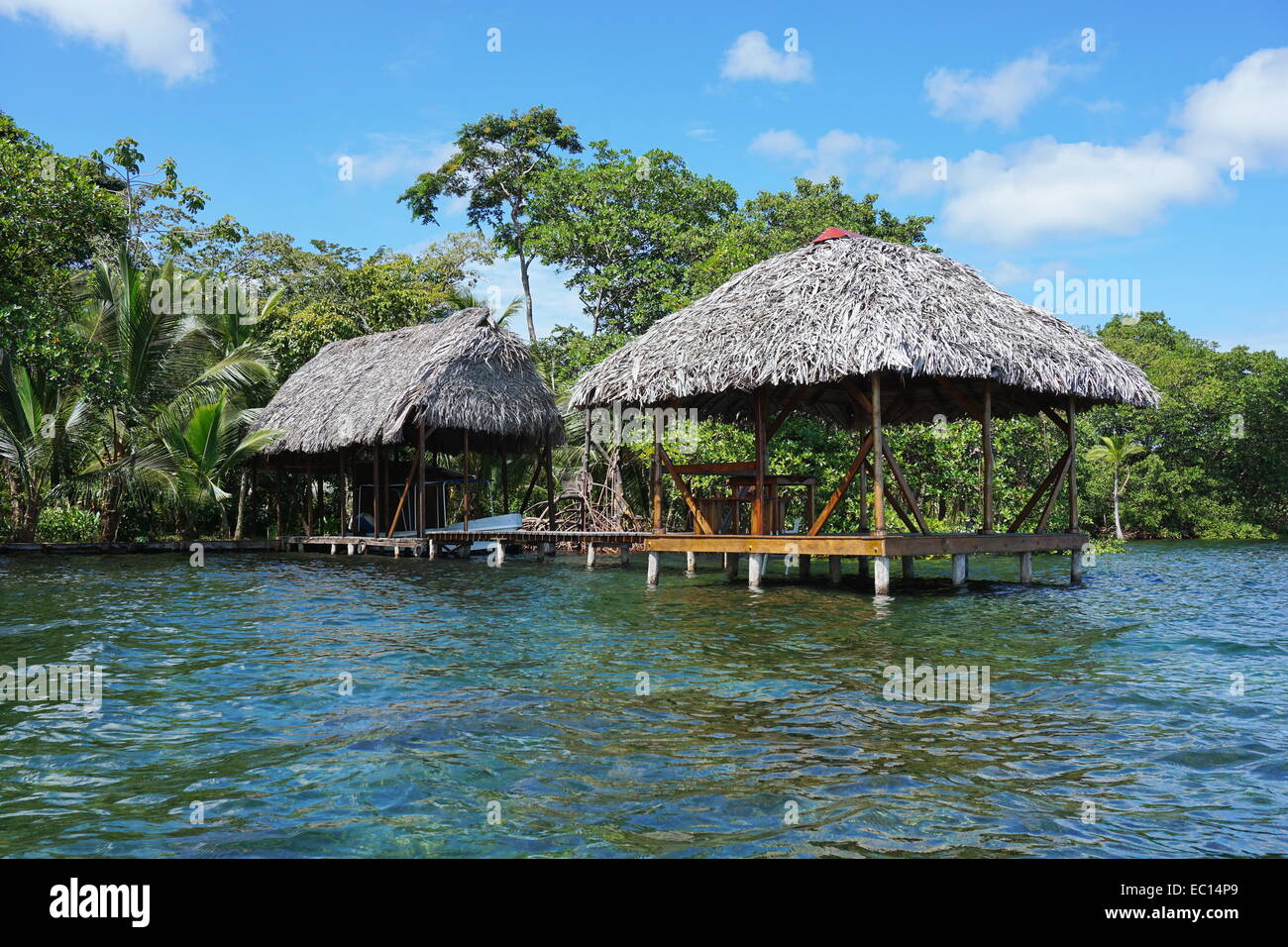Albergo sul fronte spiaggia con paglia rifugio tropicale e il boathouse oltre il mare dei Caraibi, Panama Foto Stock