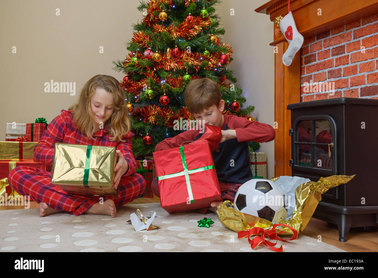 Due bambini, un ragazzo e una ragazza, aprendo loro presenta la mattina di natale. Foto Stock