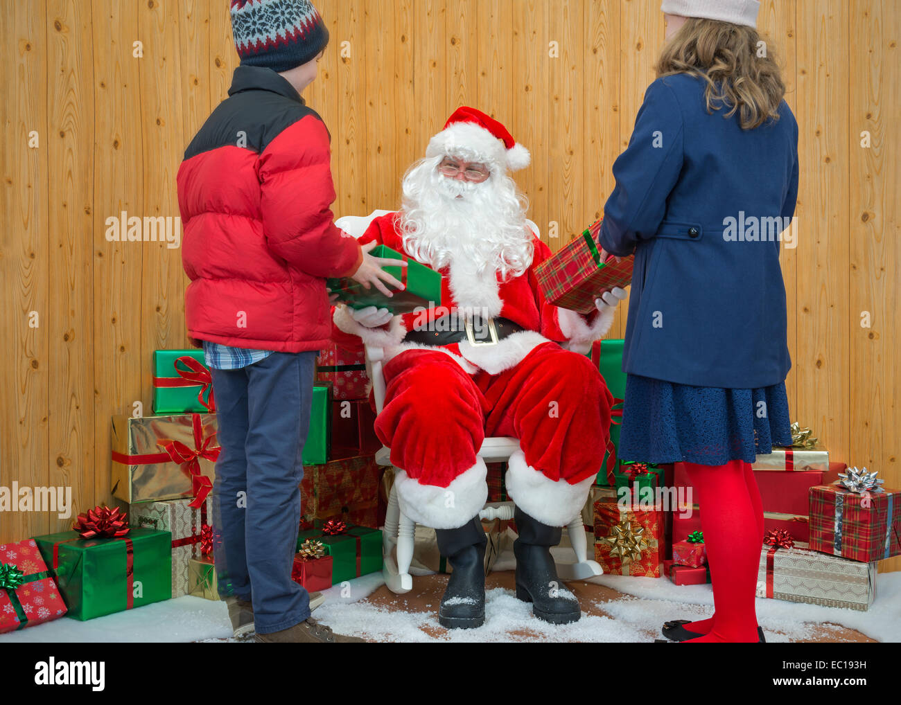 Un ragazzo e una ragazza ricevere regali di Natale da Santa nella sua grotta Foto Stock