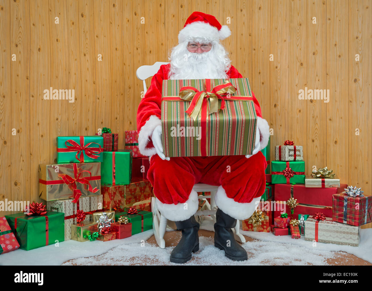 Babbo Natale / Babbo Natale seduto nella sua grotta tenendo un regalo per te. Foto Stock