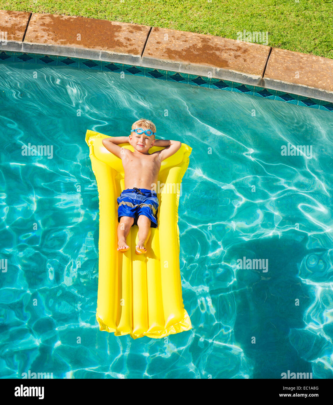 Giovane ragazzo in relax e divertimento in piscina sulla zattera di giallo. La vacanza estiva di divertimento. Stile di vita rilassante concetto. Foto Stock