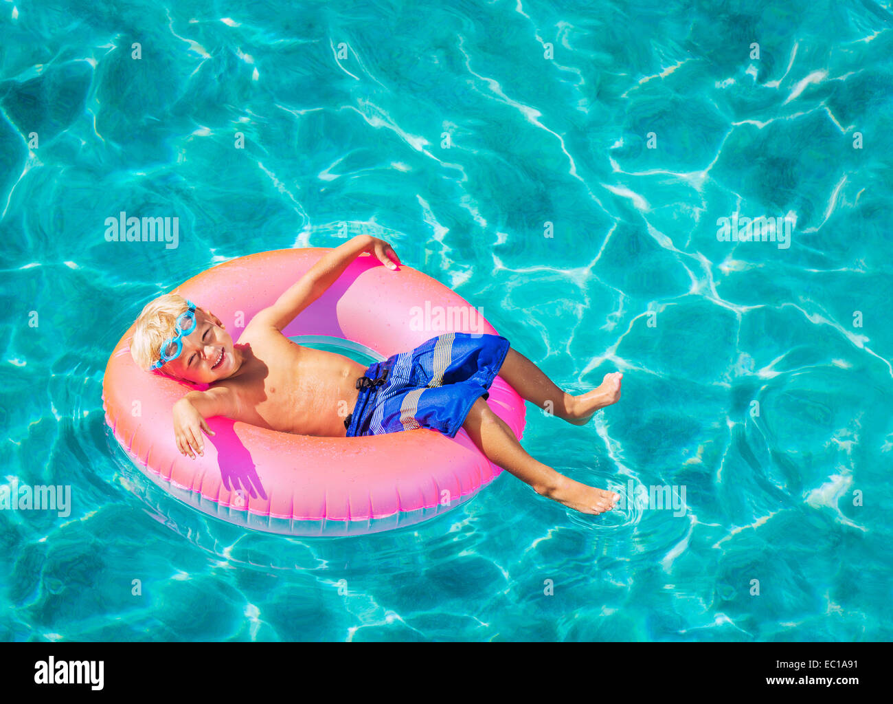 Felice Ragazzo galleggianti in piscina su zattera Foto Stock