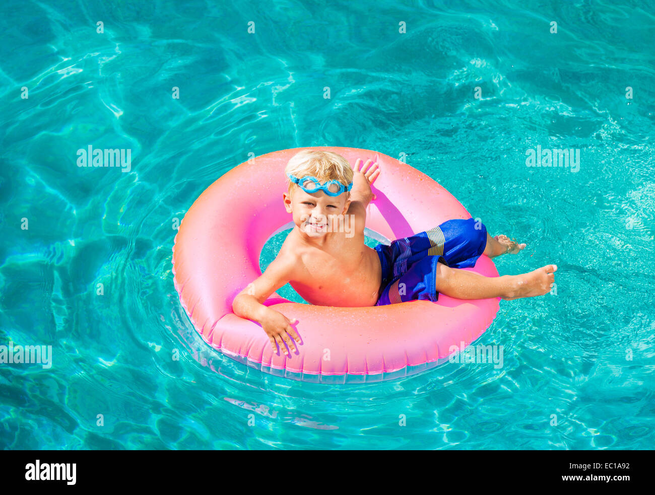 Bambino divertirsi nella piscina sul tubo interno zattera. La vacanza estiva di divertimento. Foto Stock