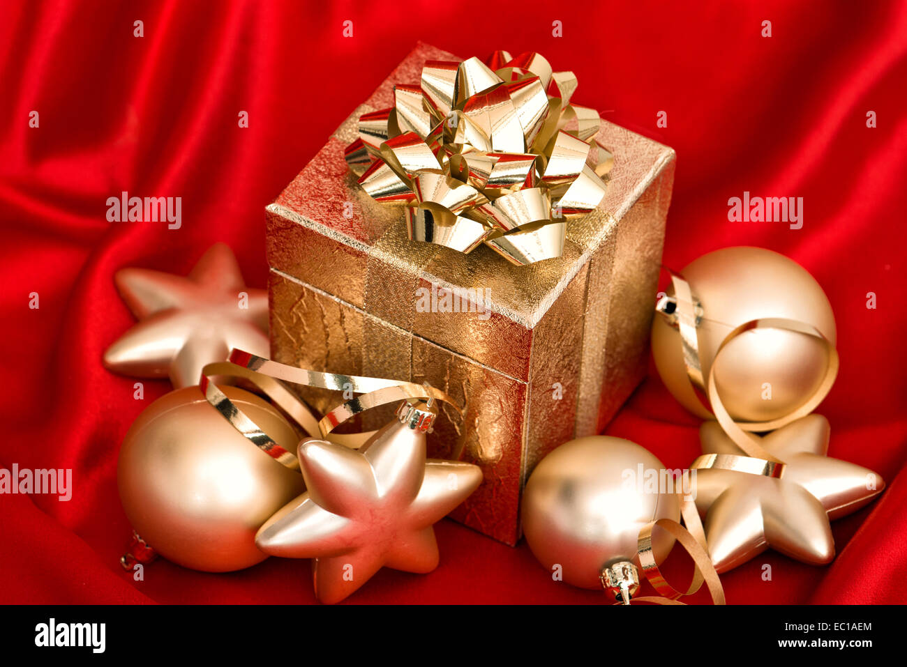 Golden palle di Natale e confezione regalo su seta rossa sullo sfondo. decorazione di festa Foto Stock