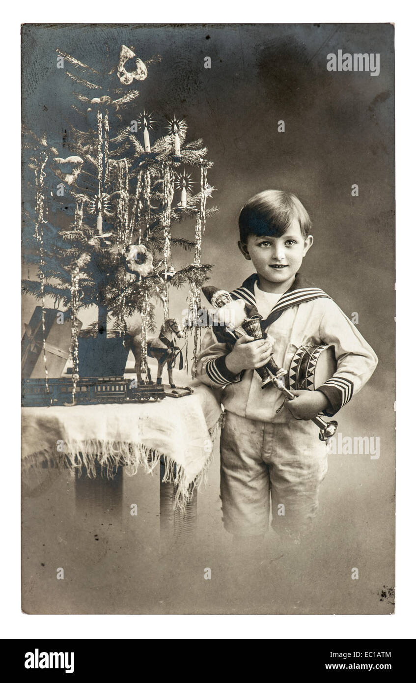 Felice ragazzo con albero di natale, regali e giocattoli d'epoca. antica immagine seppia con pellicola originale di granella e graffi Foto Stock