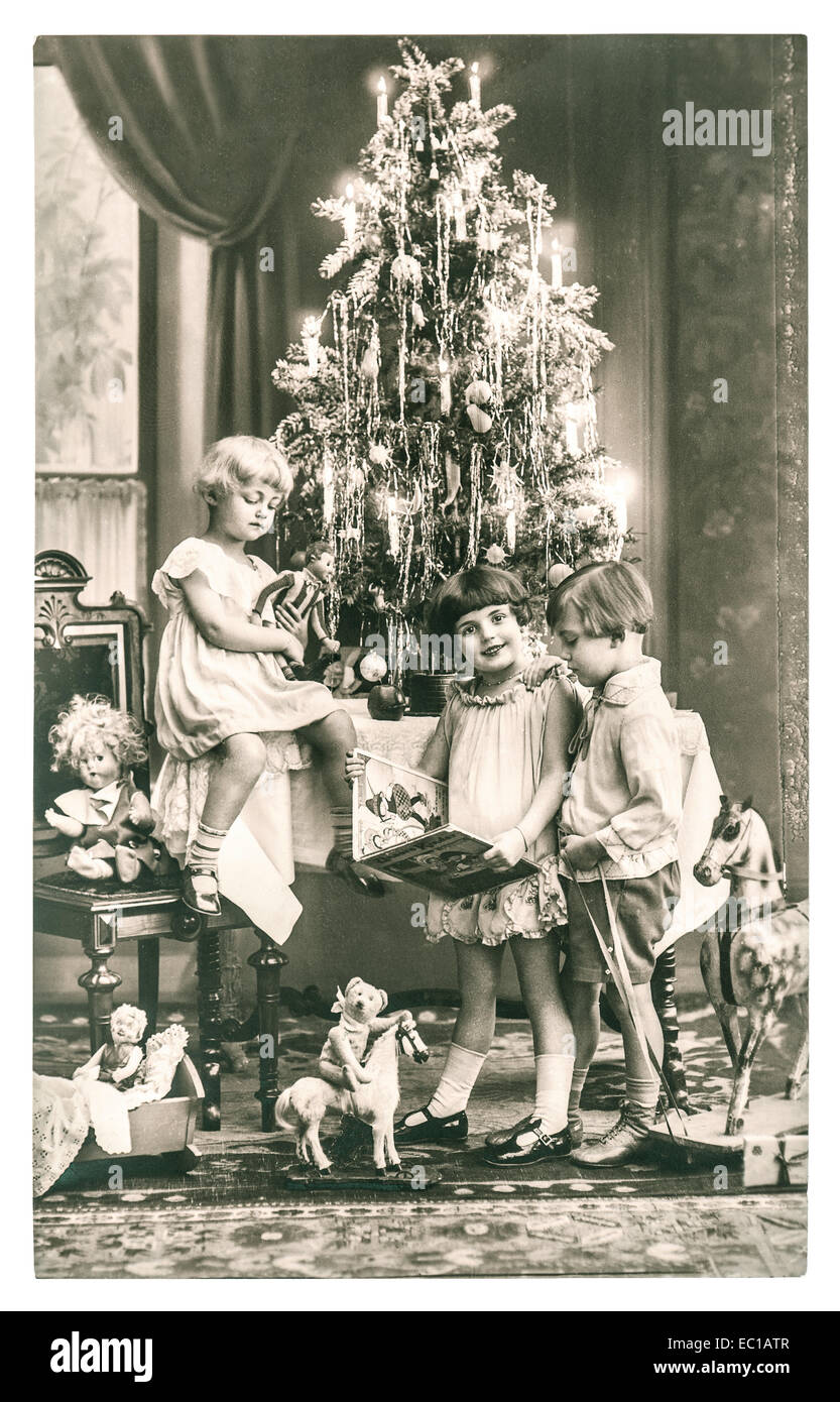 Felici i bambini con l'albero di natale, regali e giocattoli d'epoca. antica immagine seppia con originale di grana di pellicola Foto Stock