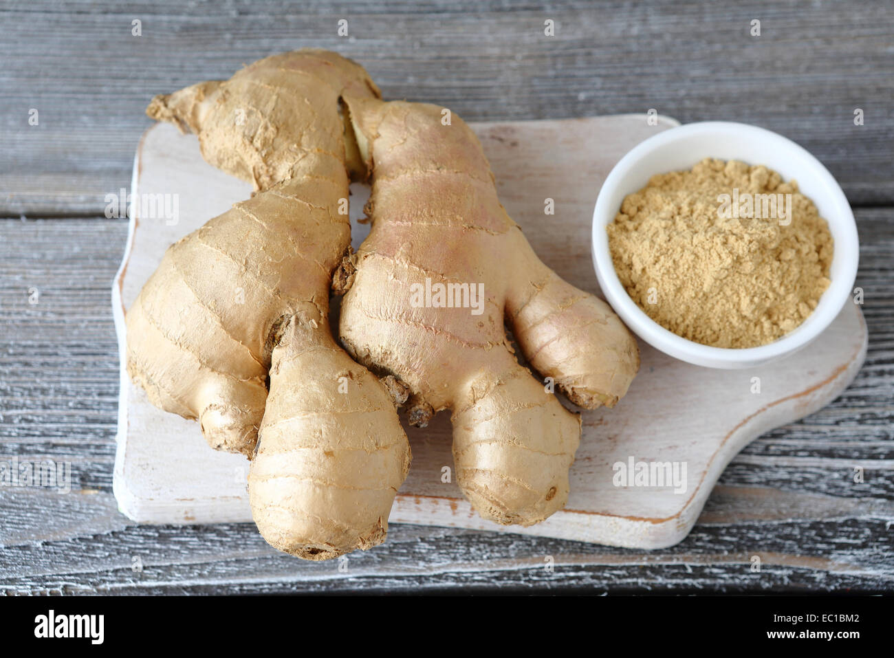 Radice di Zenzero e lo zenzero in polvere in una ciotola e speziato Foto Stock