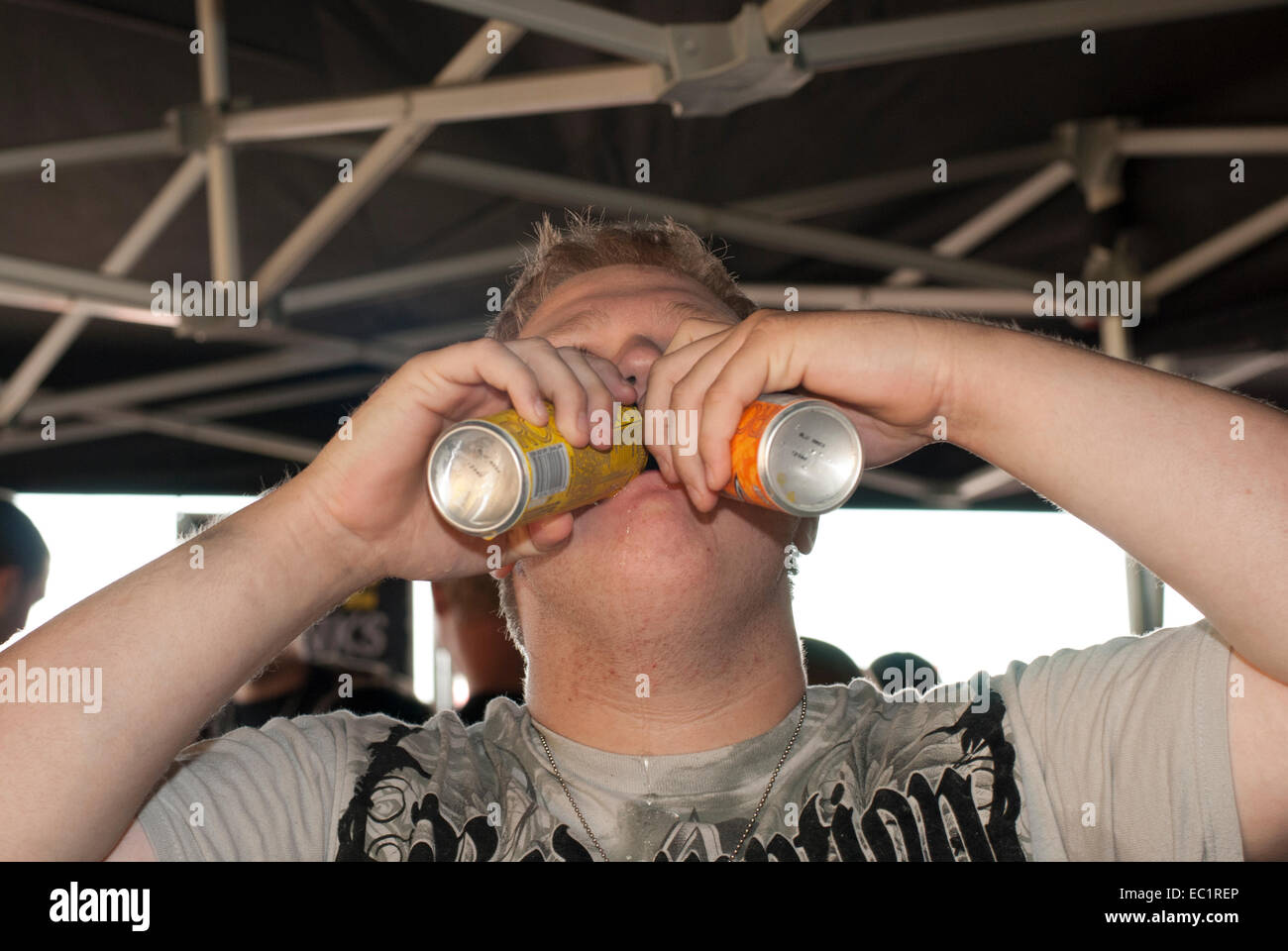 Ragazzo adolescente guzzles due bevande energetiche Foto Stock