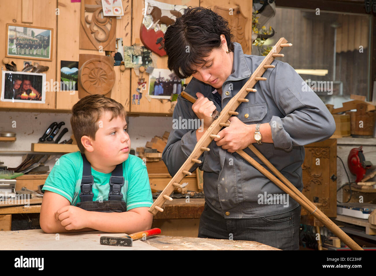 Giovane agricoltore la riparazione di un rastrello di fieno, installazione maniglia, figlio guardando, Sprenger fattoria di famiglia di Schwaz District, Tirolo Foto Stock