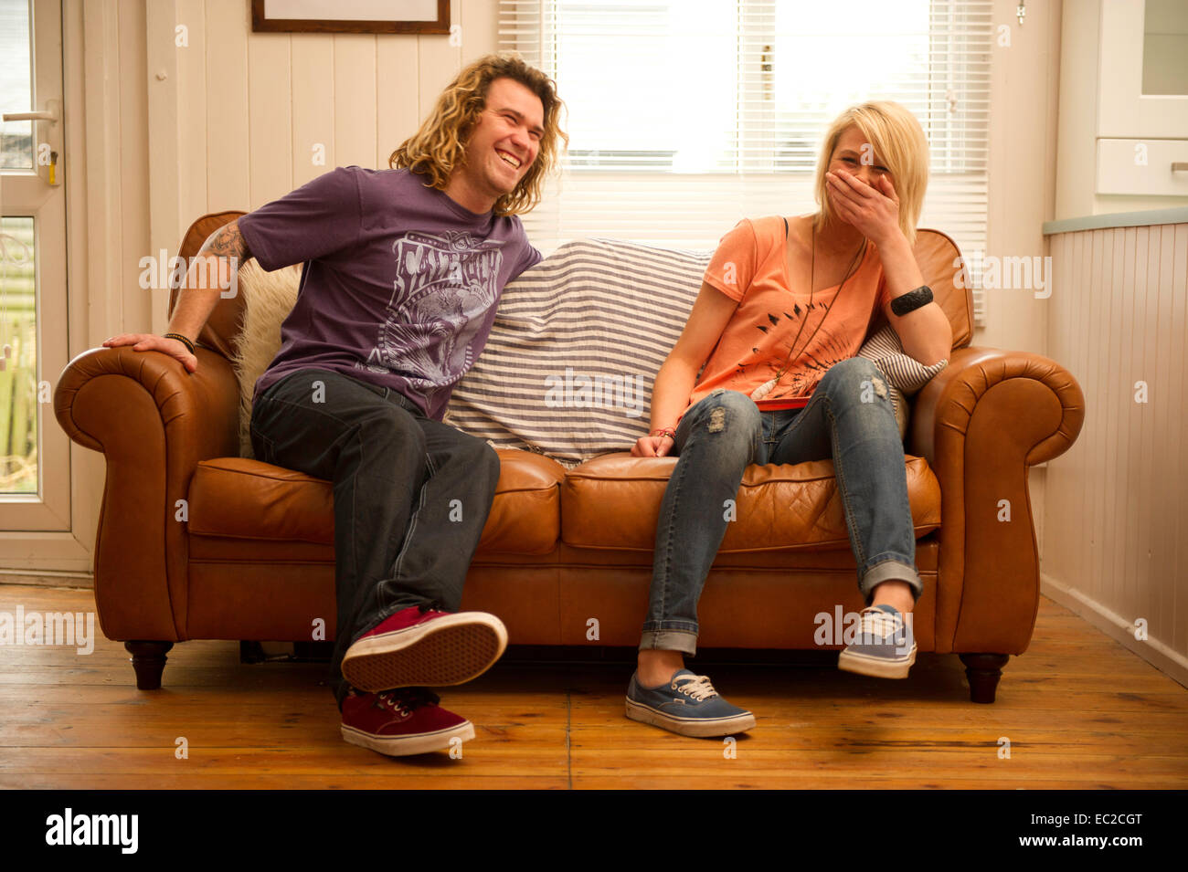 Una giovane coppia relax su un divano in pelle Foto Stock