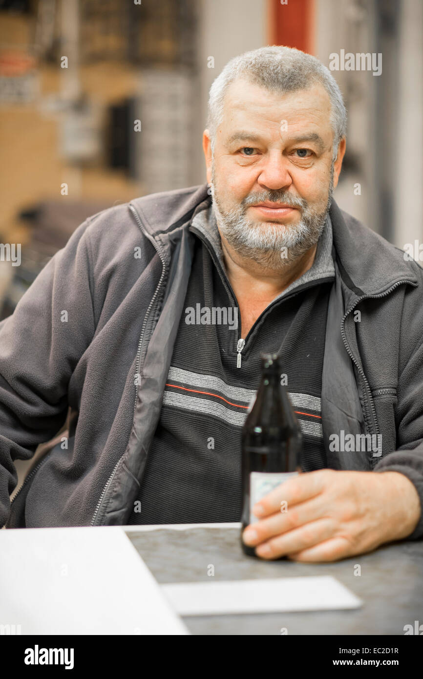 Coppia uomo caucasico con birra bootle seduti ad un tavolo nel suo negozio Foto Stock
