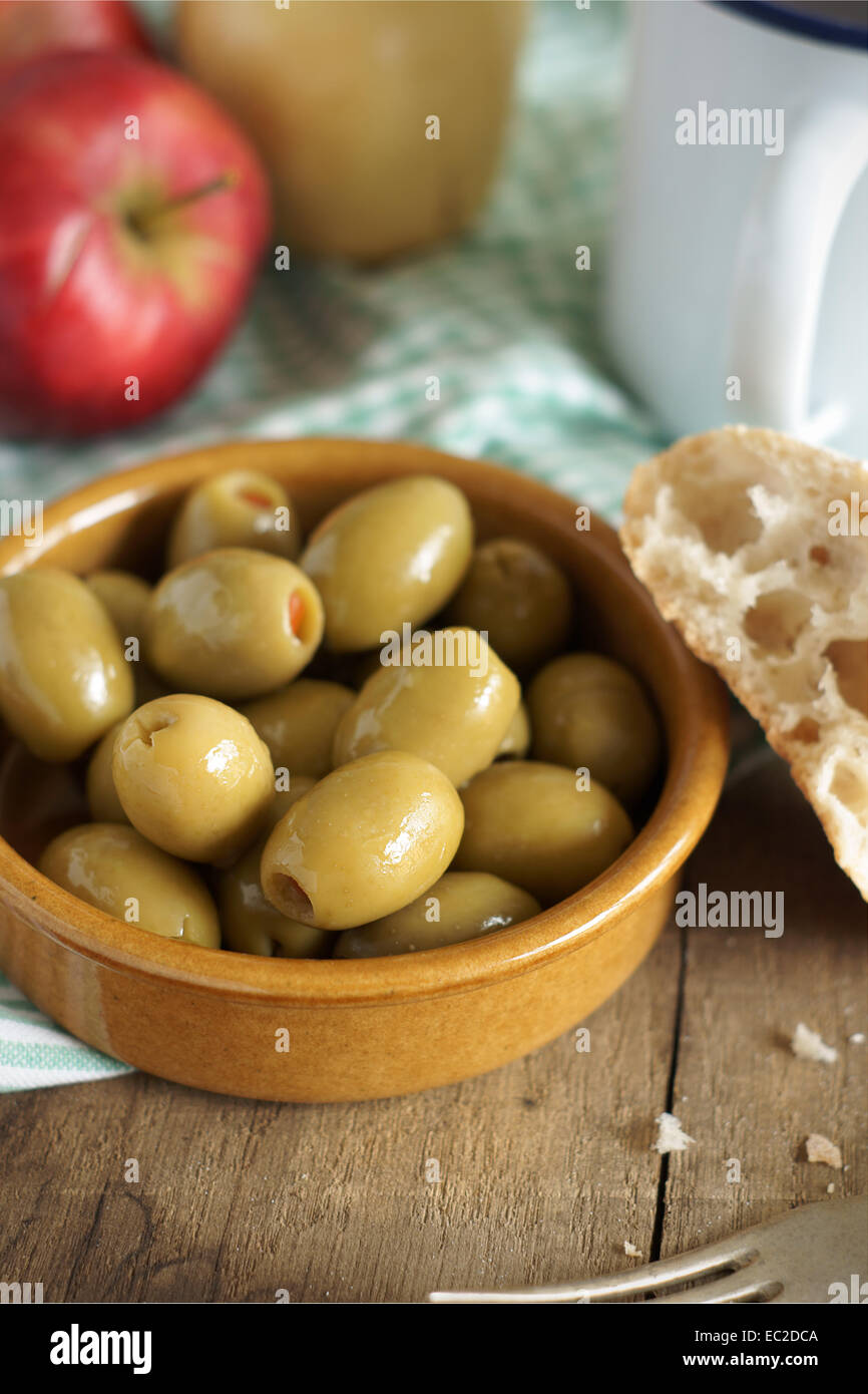 Il pimento Olive farcite in un rustico pasto impostazione. Il fuoco selettivo sulla parte anteriore oliva. Foto Stock