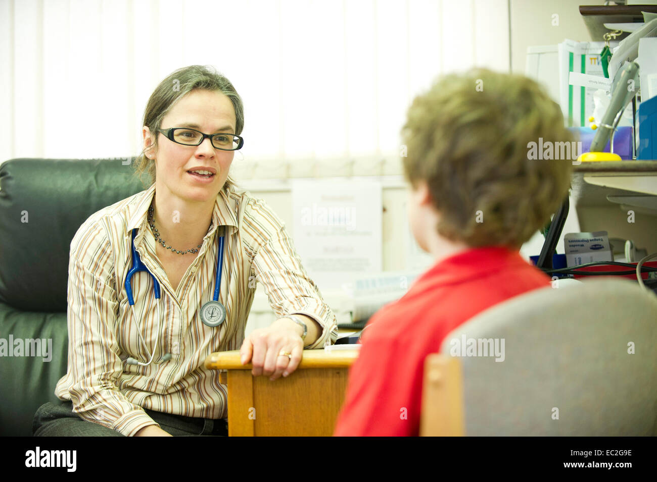 Un medico donna parlando a un giovane paziente in una chirurgia medici Foto Stock