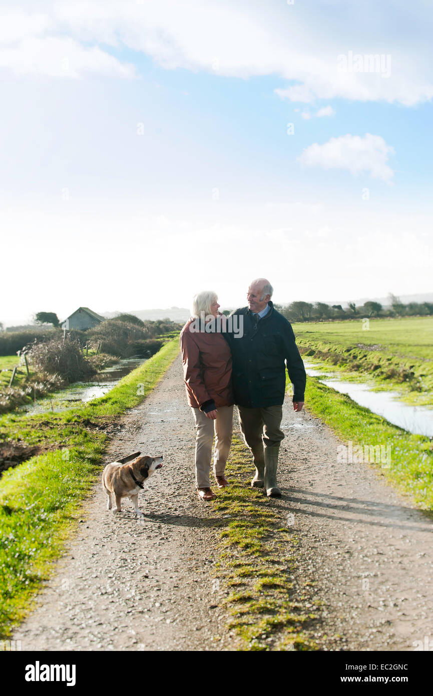 Una coppia di anziani a piedi il loro cane in campagna Foto Stock
