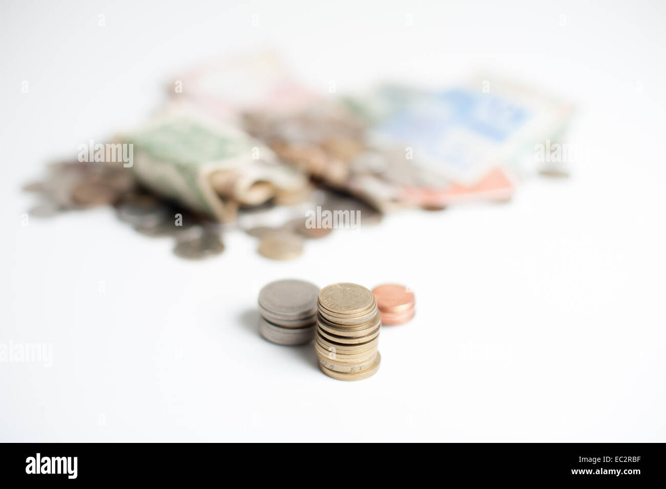 Tre pile di monete, oro, argento e bronzo, con la montagna di denaro delle monete e delle banconote in euro al di fuori della messa a fuoco in background Foto Stock