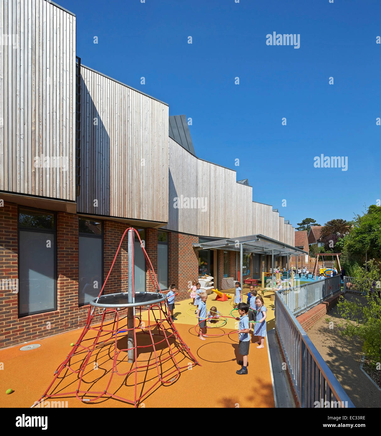 Hollymount School di Londra, Regno Unito. Architetto: Haverstock Associates LLP, 2013. Prospettiva di facciata con parco giochi e ch Foto Stock