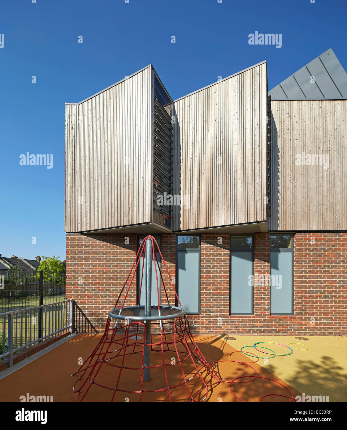 Hollymount School di Londra, Regno Unito. Architetto: Haverstock Associates LLP, 2013. Particolare della facciata esterna con parco giochi per bambini Foto Stock