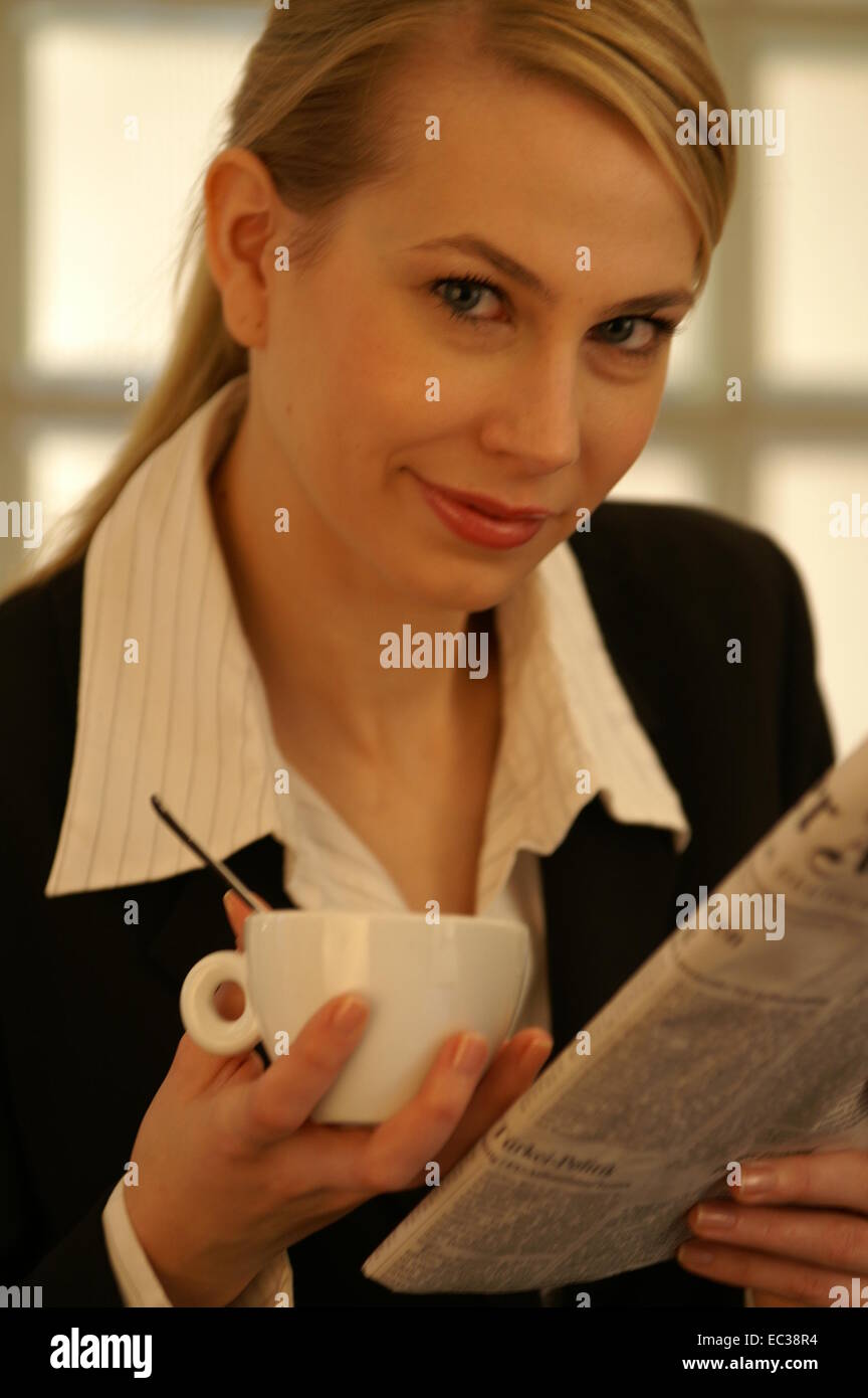 Donna con una tazza di caffè e un giornale Foto Stock