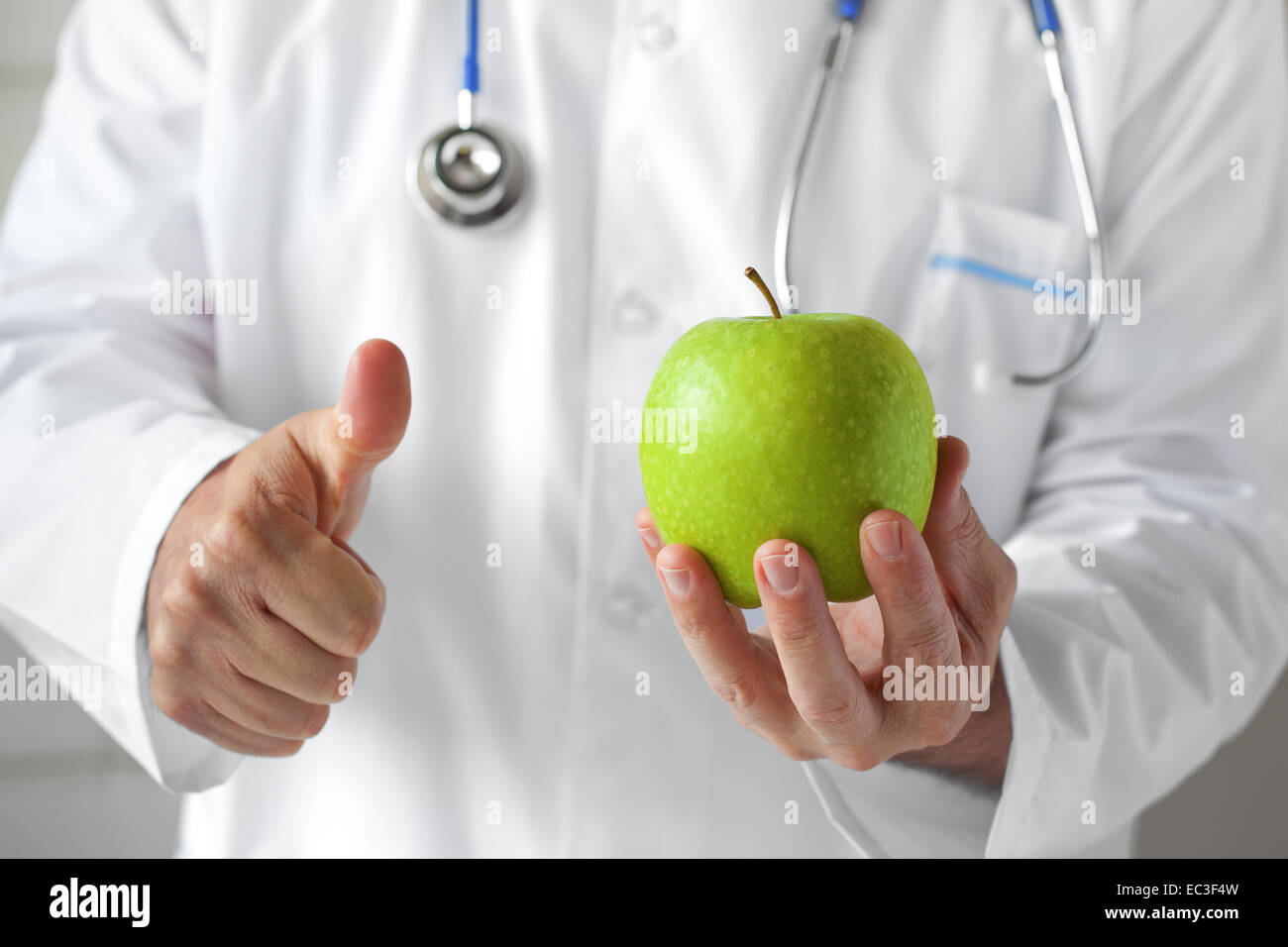 Medico con mela verde in mano nella sala di consultazione. Foto Stock