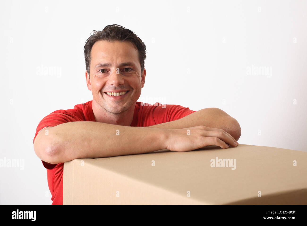 Uomo appoggiato su di una scatola di cartone Foto Stock