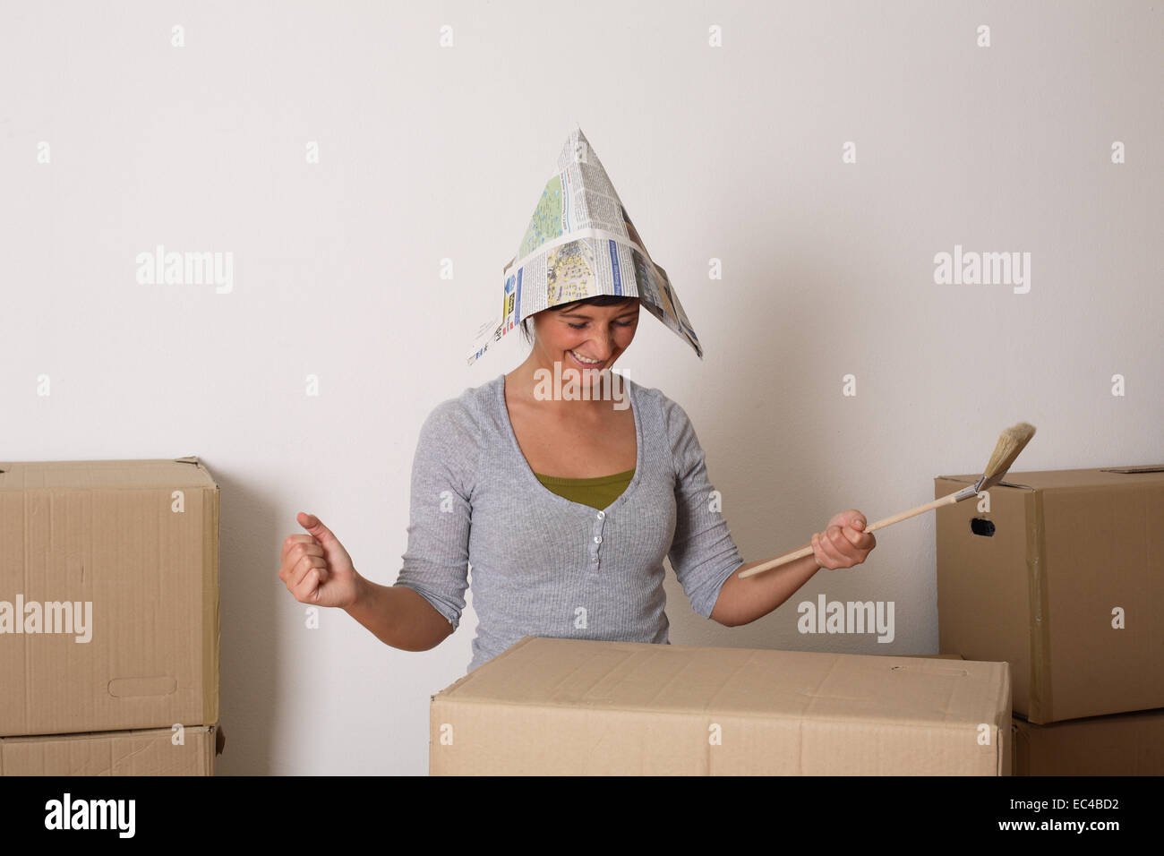Giovane donna con cappello di carta e spazzola Foto Stock
