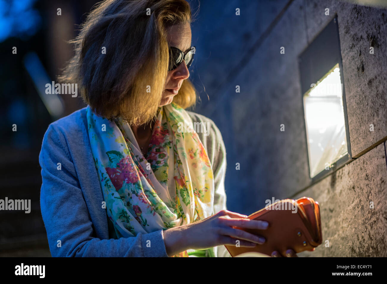 Giovane donna seduta su una scalinata e in cerca di denaro nella sua borsa Foto Stock